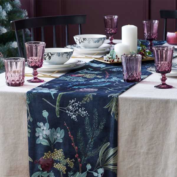Leaf printed table runner with purple glassware on a dinner table.